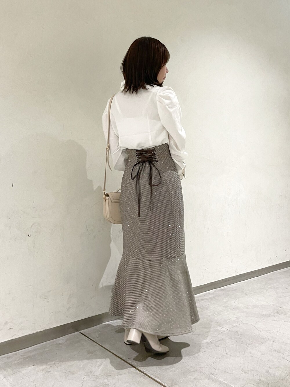 ホワイト系のシャツ/ブラウス、ブラウン系のスカート、ベージュ系のブーツを着用したレディースの秋コーディネートの7枚目の写真