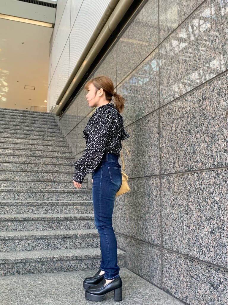 イエロー系のハンドバッグ、ベージュ系のテーラードジャケット、ブラック系のローファーを着用したレディースの冬コーディネートの3枚目の写真