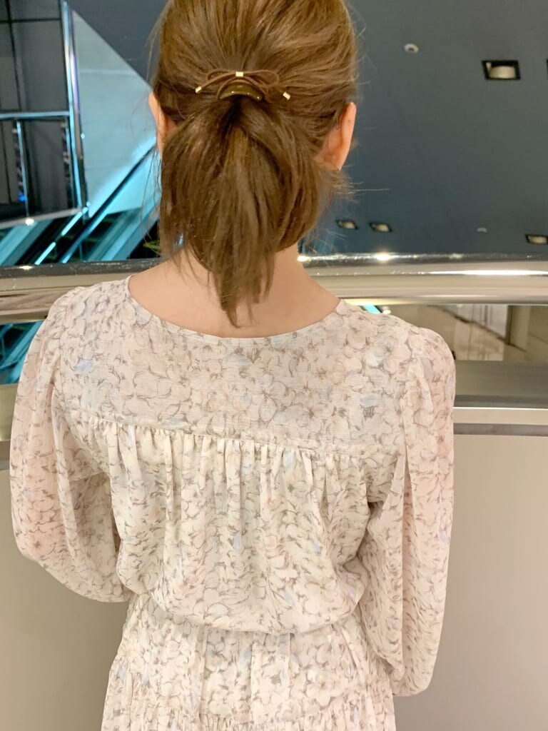 ベージュ系のトレンチコート、オレンジ系のワンピース、ホワイト系のパンプスを着用したレディースの冬コーディネートの4枚目の写真