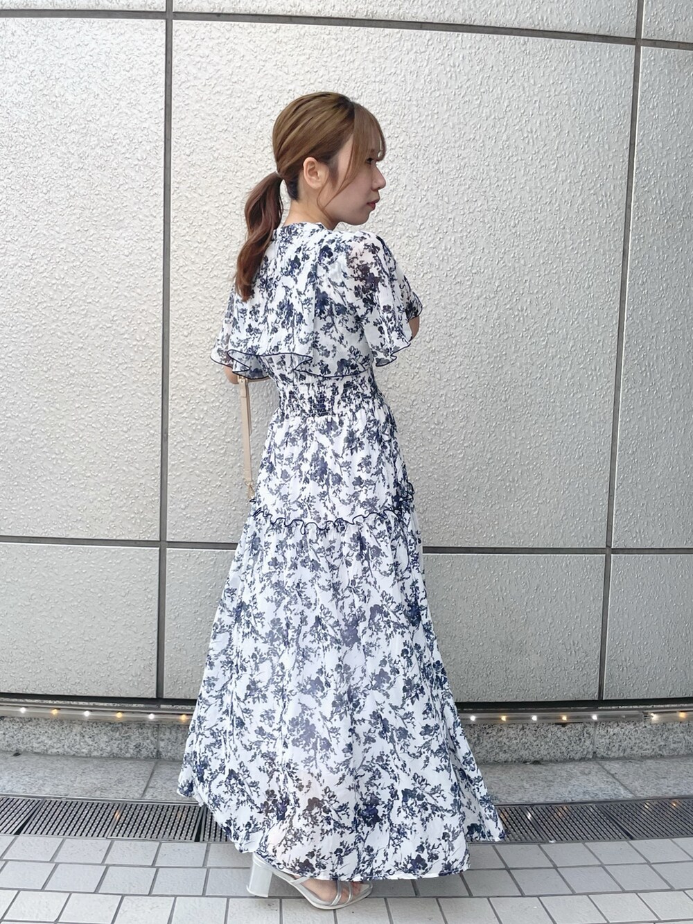 ホワイト系のワンピース、ホワイト系のハンドバッグ、シルバー系のパンプスを着用したレディースの夏コーディネートの2枚目の写真