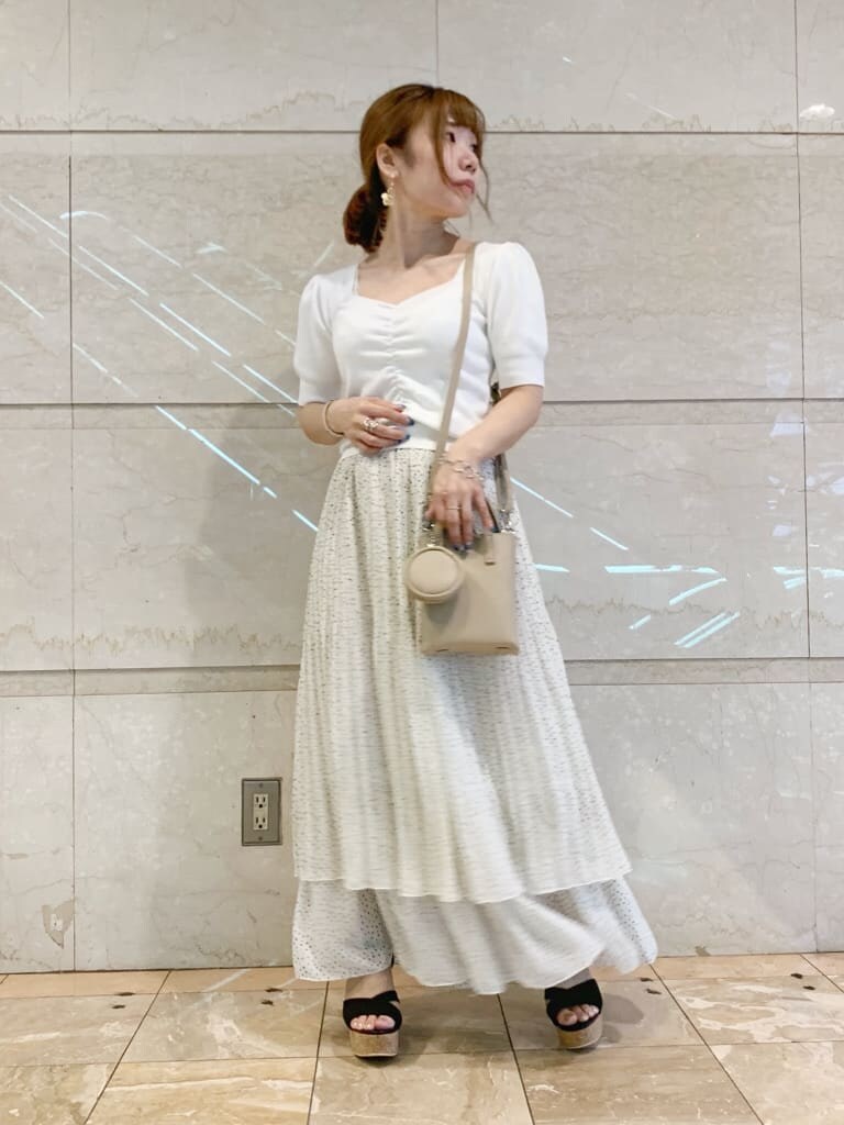 ブラック系のサンダル、ベージュ系のハンドバッグ、ホワイト系のニット/セーターを着用したレディースの夏コーディネートの2枚目の写真