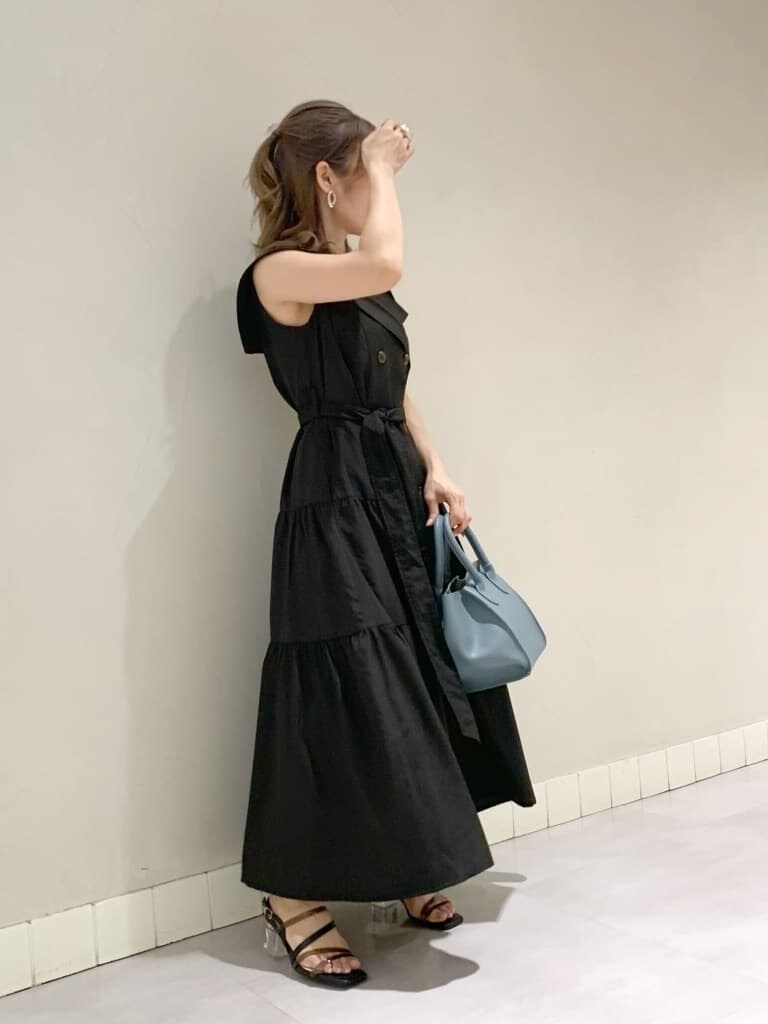 ブルー系のハンドバッグ、ブラック系のワンピース、ブラック系のサンダルを着用したレディースの春コーディネートの2枚目の写真