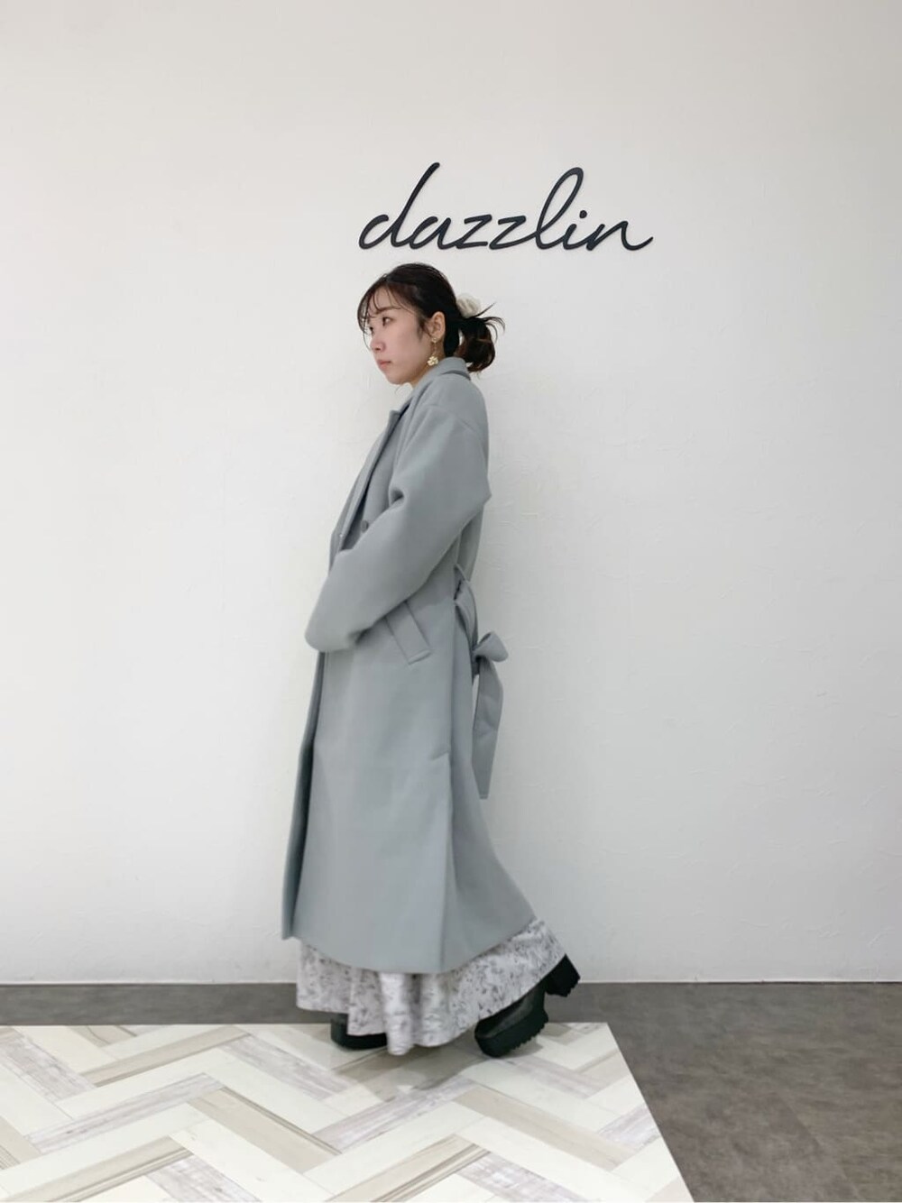 グレー系のブーツ、ブルー系のチェスターコート、グレー系のワンピースを着用したレディースの冬コーディネートの3枚目の写真