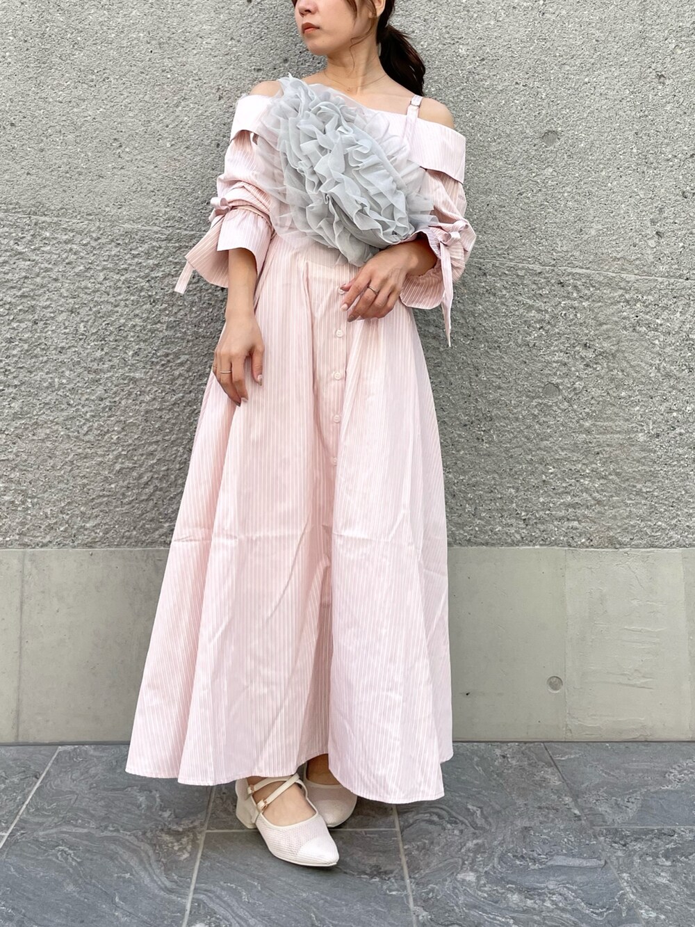 ピンク系のシャツワンピース、グレー系のベスト、ホワイト系のパンプスを着用したレディースの春コーディネートの3枚目の写真