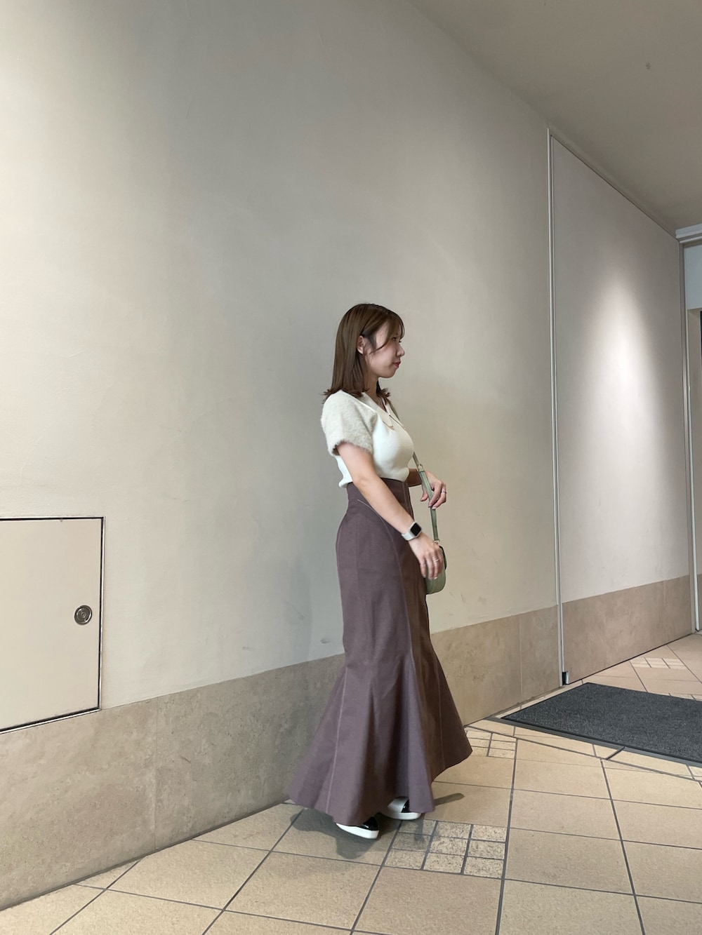 ホワイト系のニット/セーター、グリーン系のハンドバッグ、ブラウン系のスカートを着用したレディースの秋コーディネートの2枚目の写真