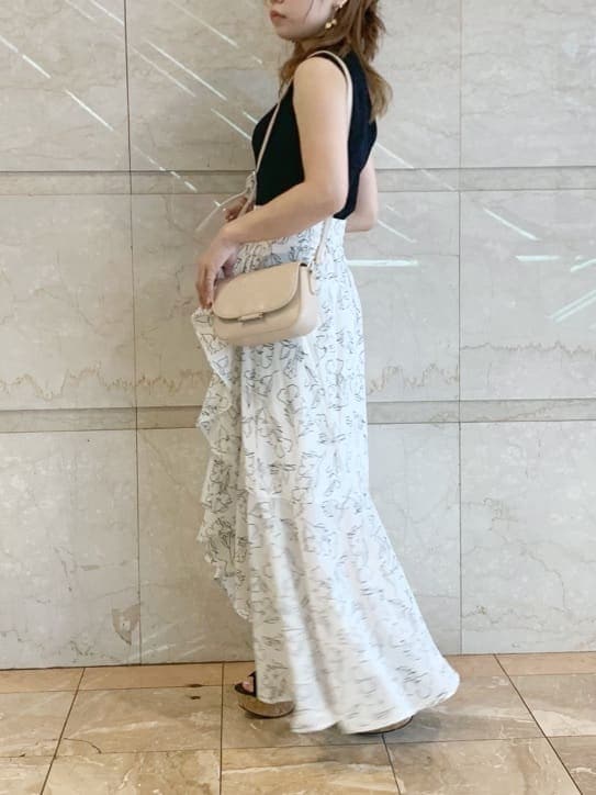 ブラック系のサンダル、ベージュ系のショルダーバッグ、ホワイト系のスカートを着用したレディースの春コーディネートの2枚目の写真
