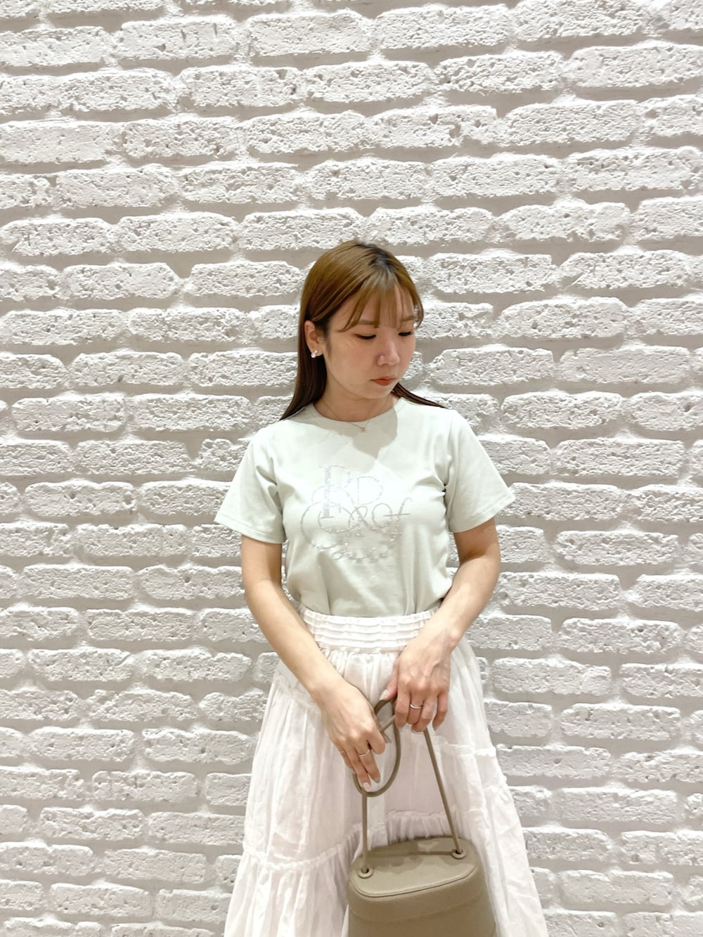 グリーン系のTシャツ/カットソー、ホワイト系のスカート、シルバー系のパンプスを着用したレディースの春コーディネートの5枚目の写真