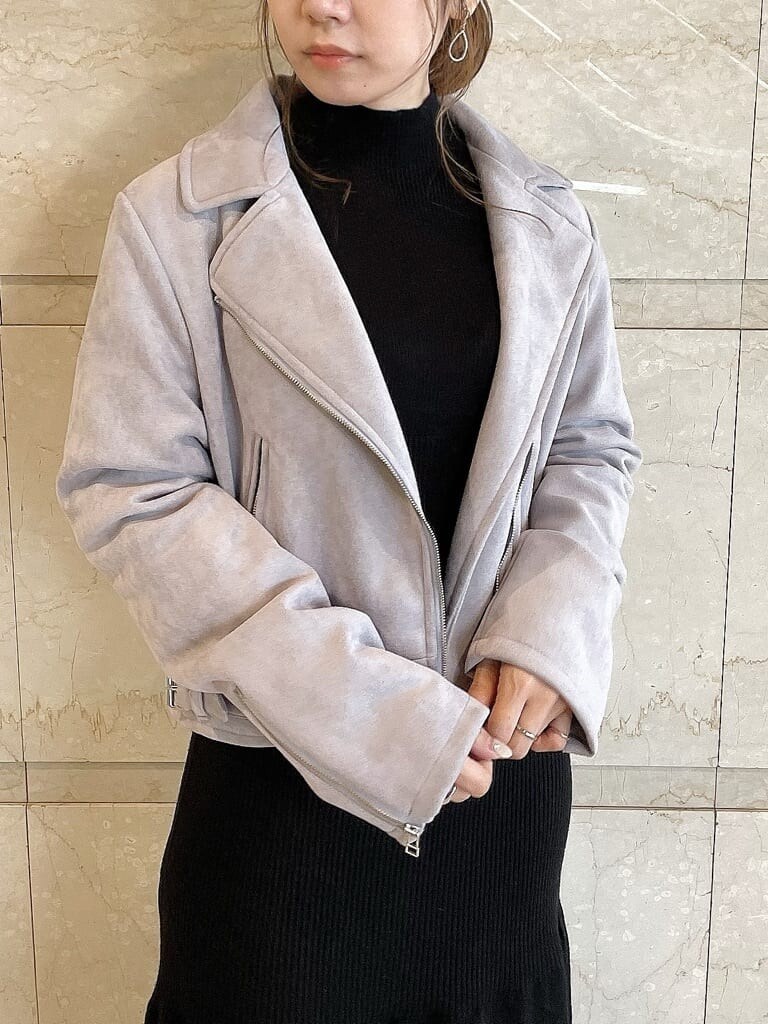 パープル系のライダースジャケット、ベージュ系のブーツ、ブラック系のワンピースを着用したレディースの秋コーディネートの4枚目の写真