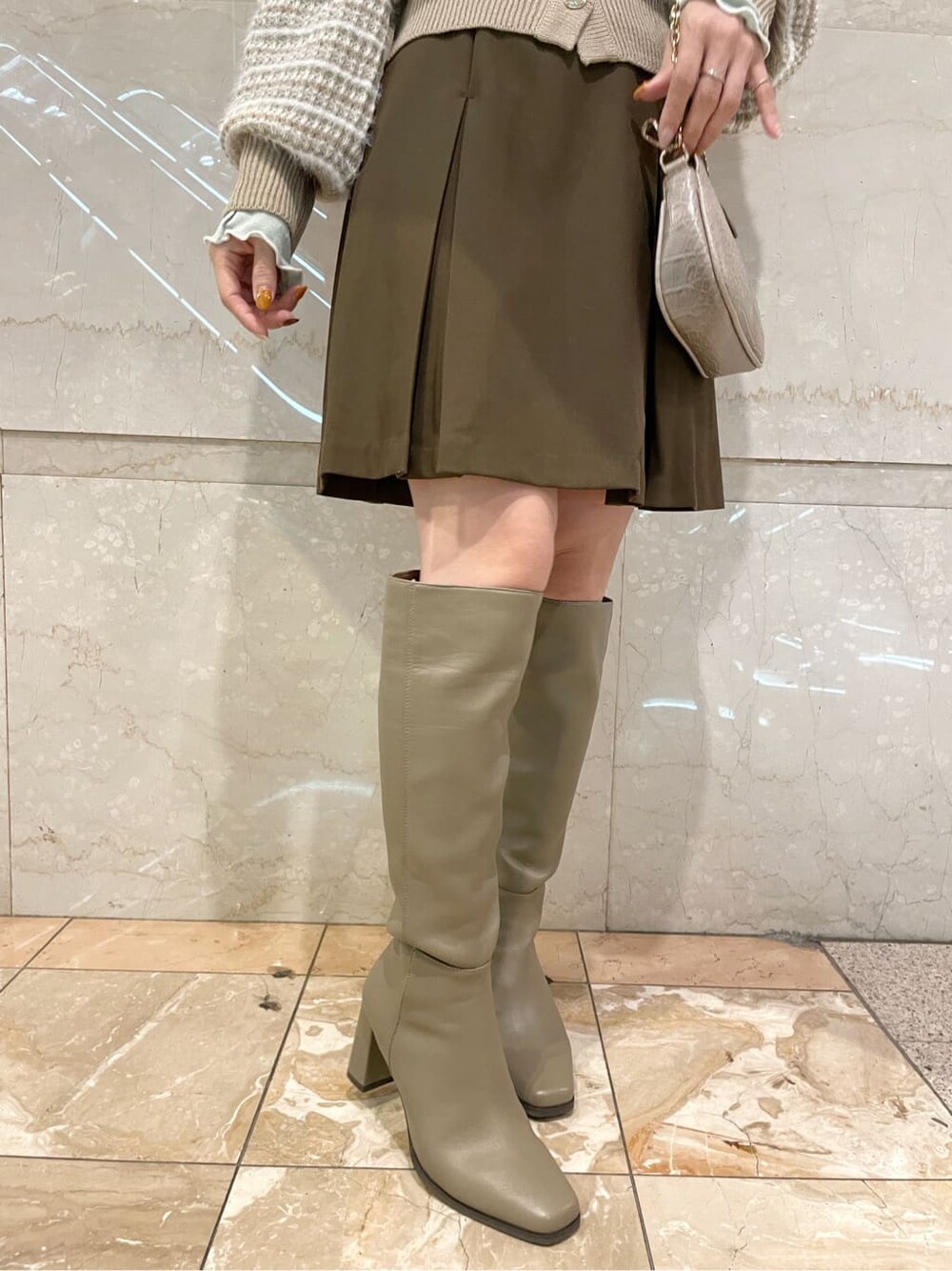 ブラウン系のスカート、ベージュ系のブーツ、ベージュ系のカーディガン/ボレロを着用したレディースの秋コーディネートの6枚目の写真