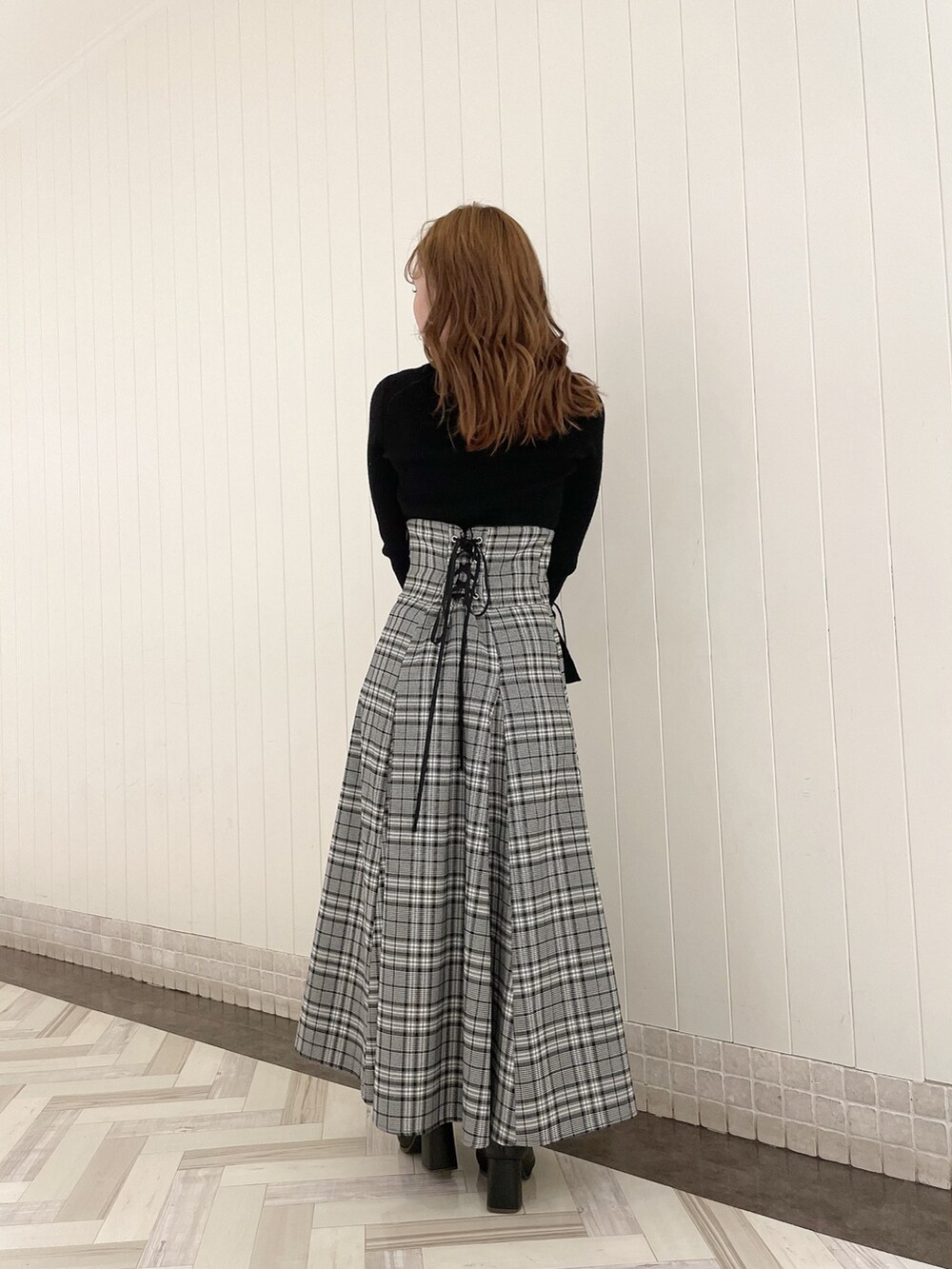 ブラック系のニット/セーター、グレー系のスカート、ブラック系のブーツを着用したレディースの秋コーディネートの3枚目の写真