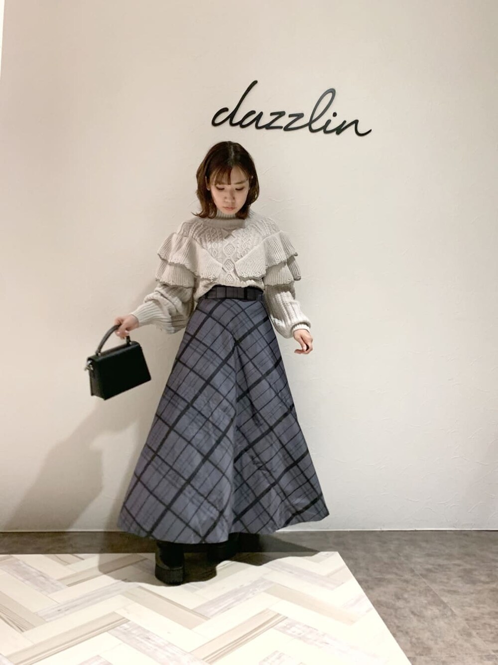 ブラック系のハンドバッグ、グレー系のスカート、グレー系のブーツを着用したレディースの秋コーディネートの5枚目の写真