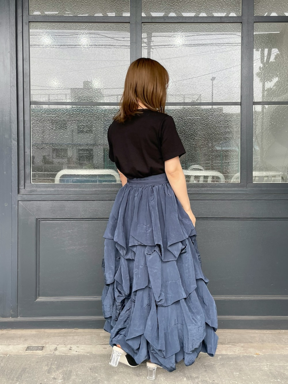 ブラック系のTシャツ/カットソー、ブラック系のかごバッグ、ブルー系のスカートを着用したレディースの夏コーディネートの2枚目の写真