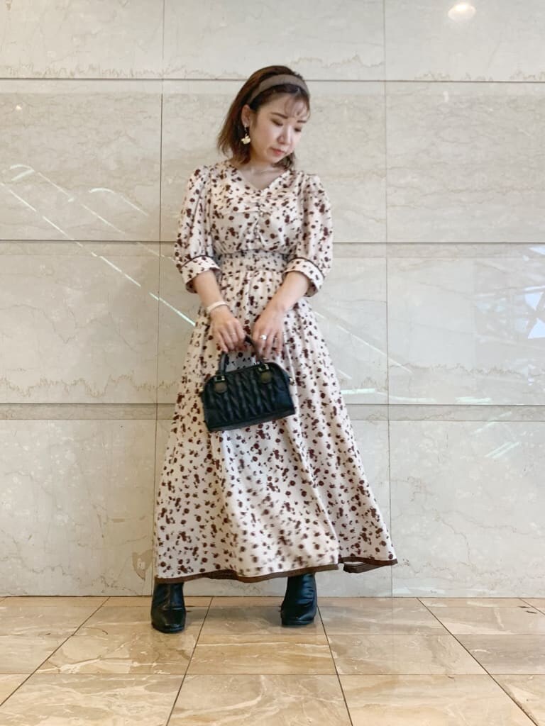 ブラック系のハンドバッグ、ブラック系のブーツ、ベージュ系のワンピースを着用したレディースの夏コーディネートの2枚目の写真