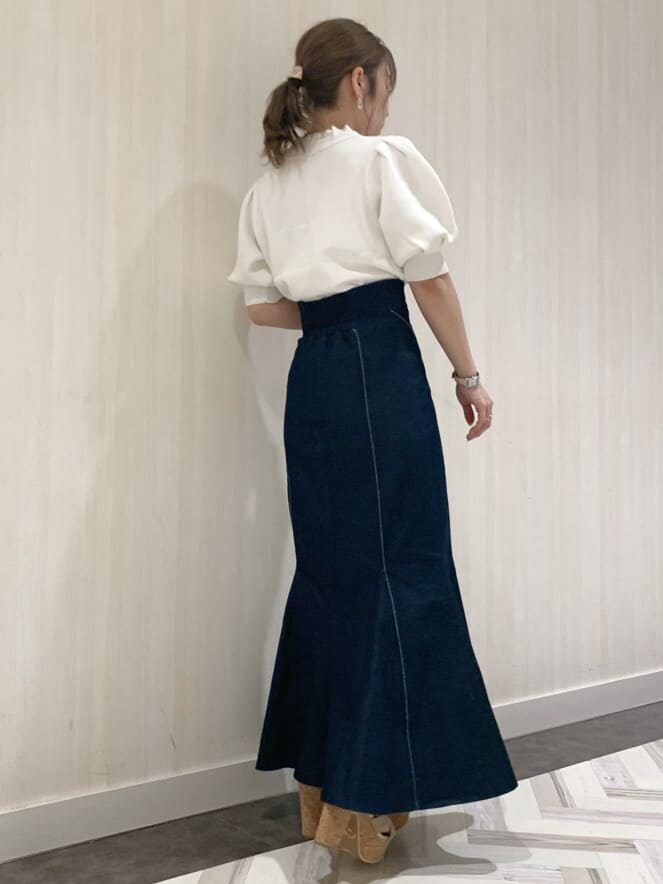 ブルー系のスカート、ホワイト系のニット/セーター、ベージュ系のサンダルを着用したレディースの春コーディネートの3枚目の写真