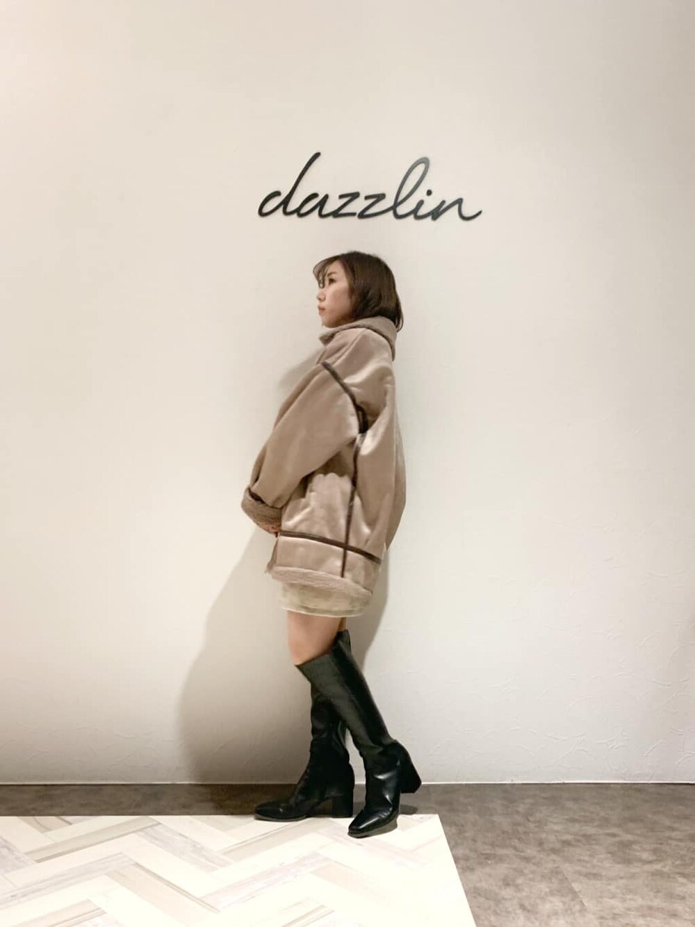 ベージュ系のブルゾン、ベージュ系のスカート、ブラック系のブーツを着用したレディースの秋コーディネートの5枚目の写真