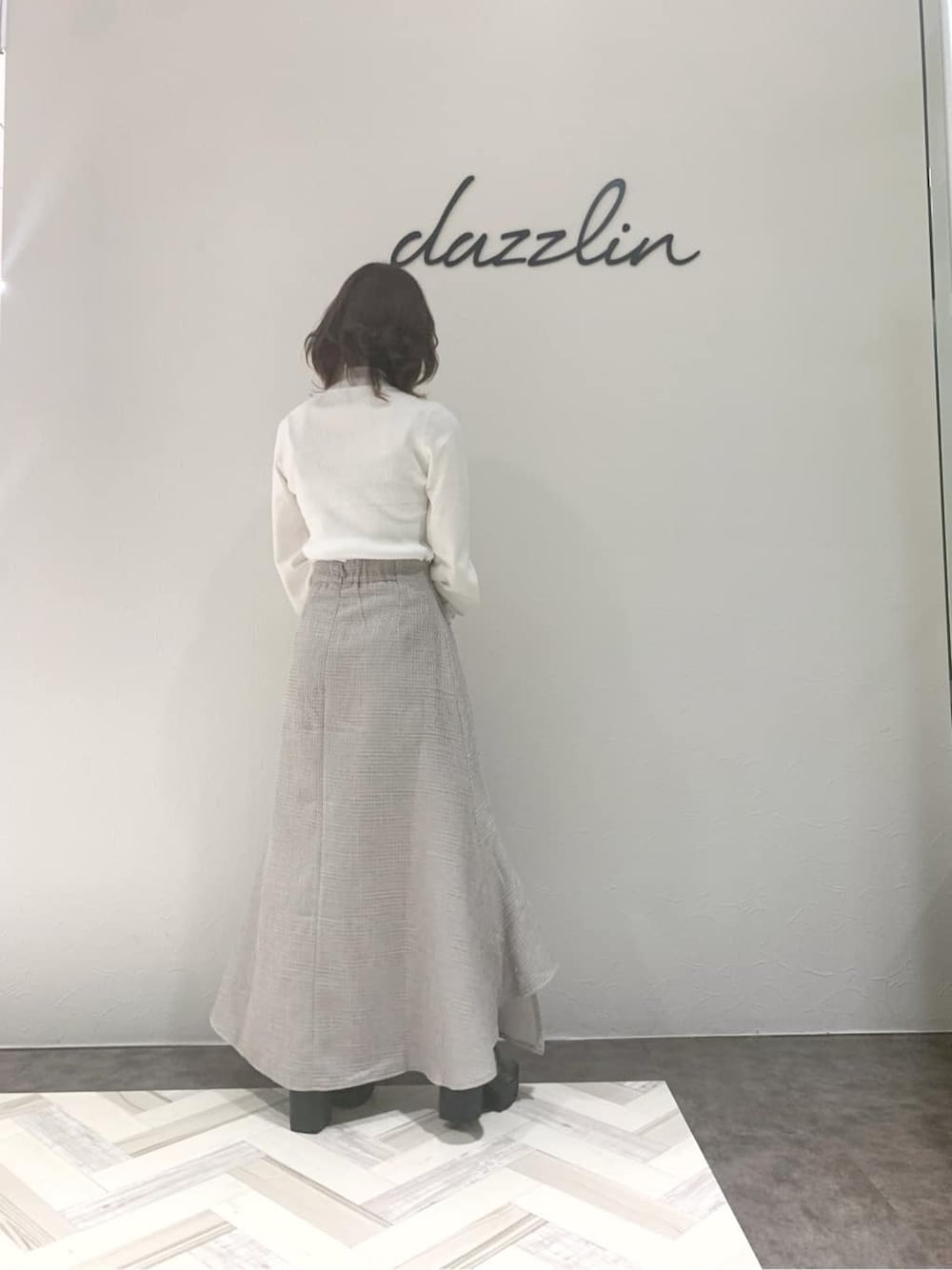 グレー系のブーツ、グレー系のスカート、ベージュ系のハンドバッグを着用したレディースの秋コーディネートの7枚目の写真