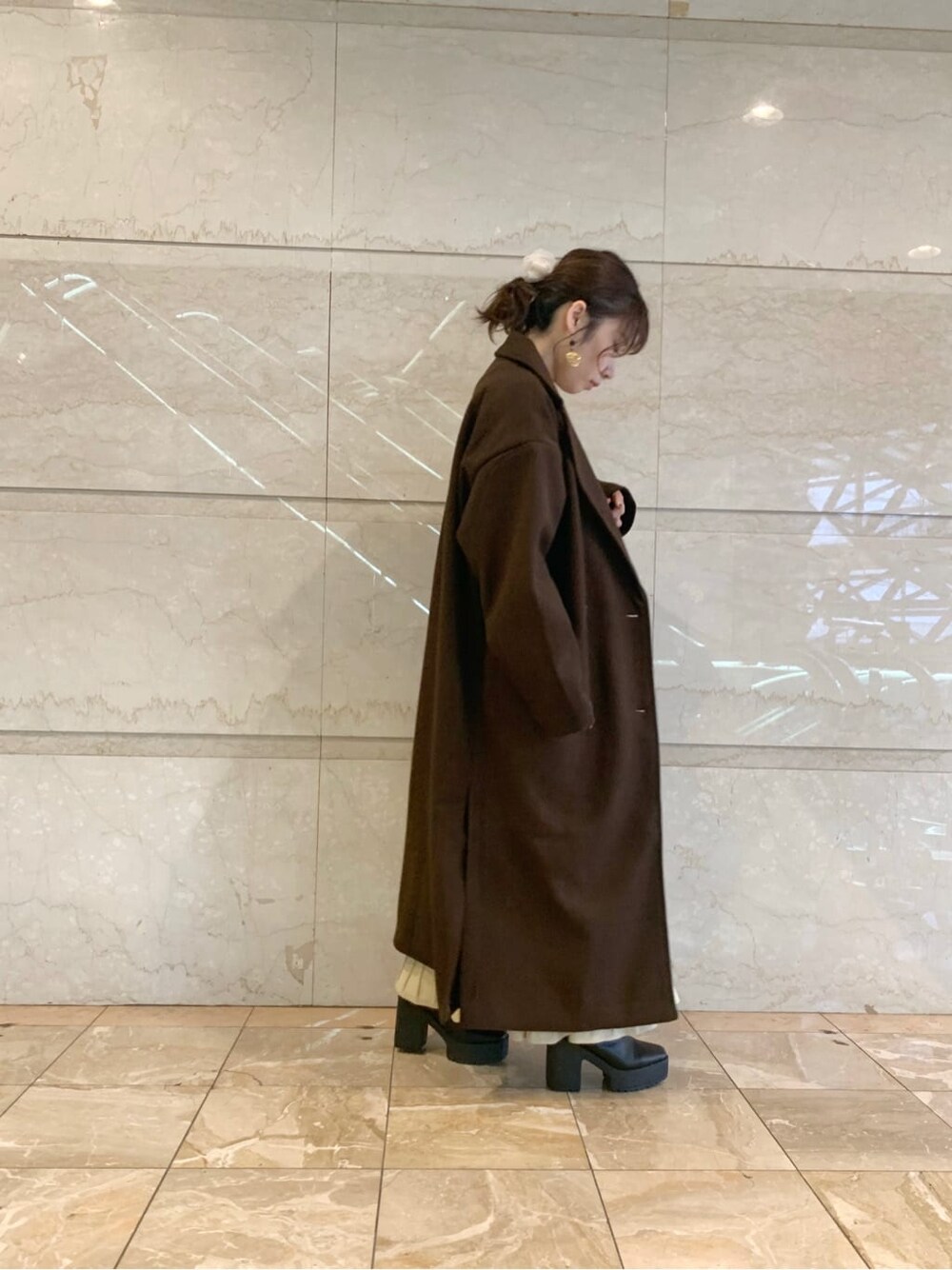 ブラック系のブーツ、ブラウン系のチェスターコート、ベージュ系のワンピースを着用したレディースの冬コーディネートの7枚目の写真