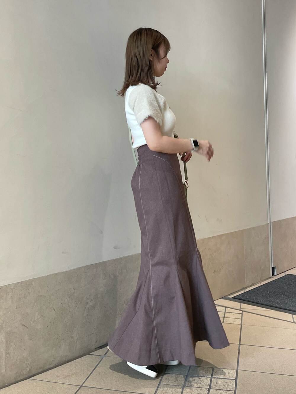 ホワイト系のニット/セーター、グリーン系のハンドバッグ、ブラウン系のスカートを着用したレディースの秋コーディネートの3枚目の写真