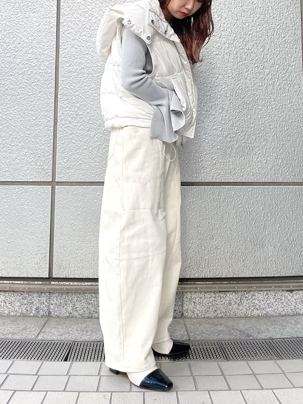 グレー系のニット/セーター、ホワイト系のダウンジャケット/コート、ホワイト系のデニムパンツを着用したレディースの冬コーディネートの2枚目の写真