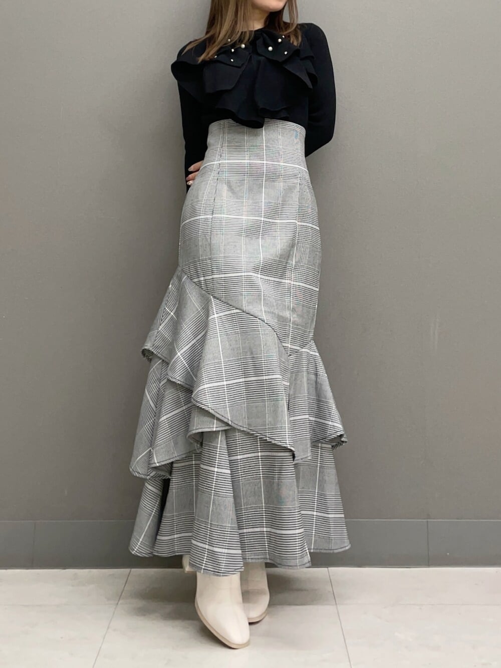 ホワイト系のブーツ、ブラック系のニット/セーター、その他のスカートを着用したレディースの秋コーディネートの2枚目の写真