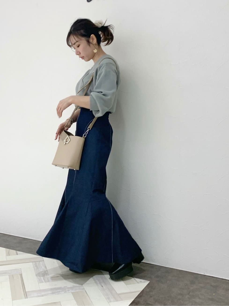 ブラック系のブーツ、ベージュ系のハンドバッグ、グリーン系のニット/セーターを着用したレディースの冬コーディネートの4枚目の写真