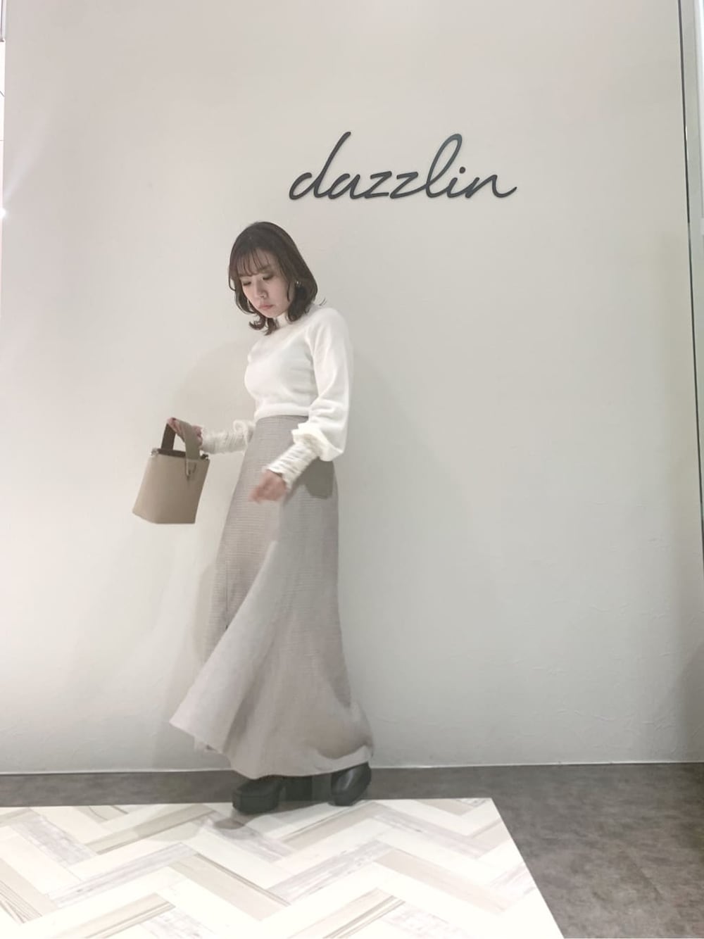 グレー系のブーツ、グレー系のスカート、ベージュ系のハンドバッグを着用したレディースの秋コーディネートの5枚目の写真