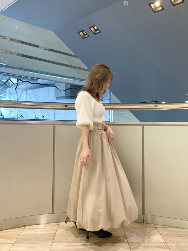 ベージュ系のスカート、ホワイト系のニット/セーター、ブラック系のブーツを着用したレディースの冬コーディネートの3枚目の写真