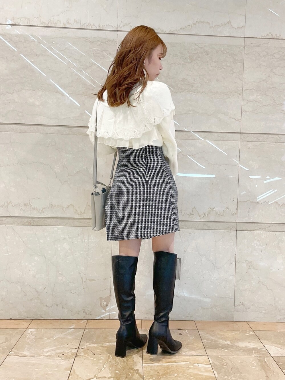 ホワイト系のニット/セーター、ブルー系のスカート、ブラック系のブーツを着用したレディースの秋コーディネートの5枚目の写真