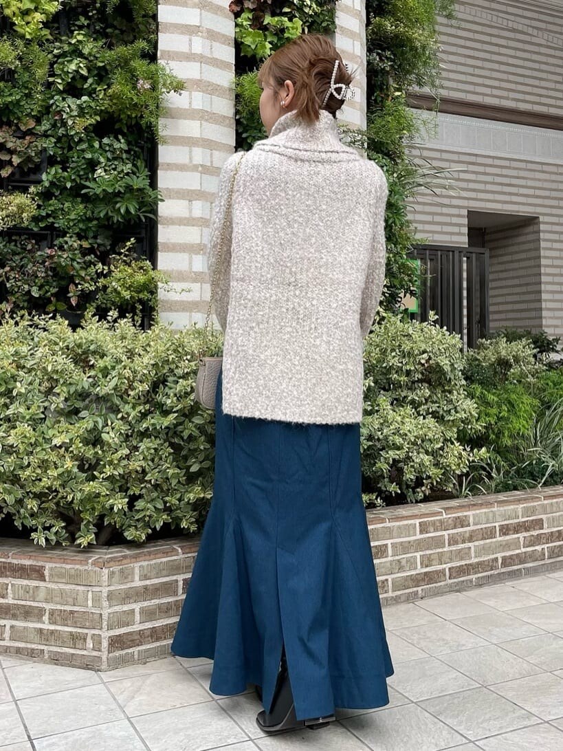 ブラック系のブーツ、ホワイト系のニット/セーター、ブルー系のスカートを着用したレディースの秋コーディネートの2枚目の写真