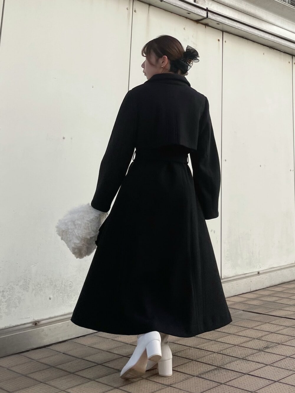 ホワイト系のハンドバッグ、ブラック系のトレンチコート、ホワイト系のブーツを着用したレディースの秋コーディネートの6枚目の写真