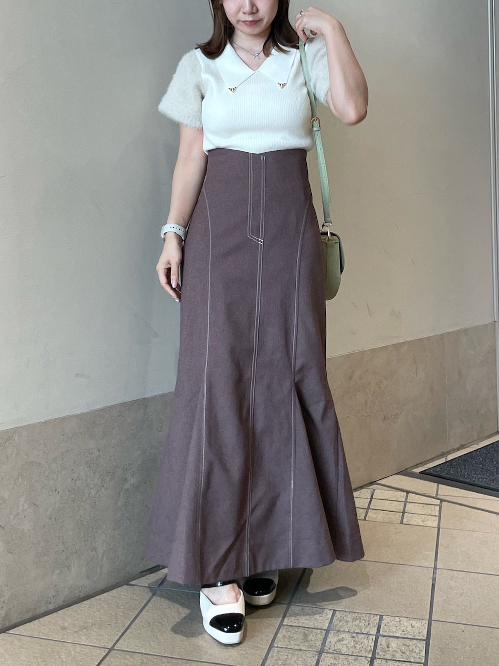 ホワイト系のニット/セーター、グリーン系のハンドバッグ、ブラウン系のスカートを着用したレディースの秋コーディネートの4枚目の写真