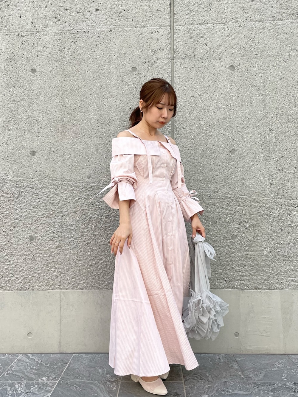 ピンク系のシャツワンピース、グレー系のベスト、ホワイト系のパンプスを着用したレディースの春コーディネートの2枚目の写真