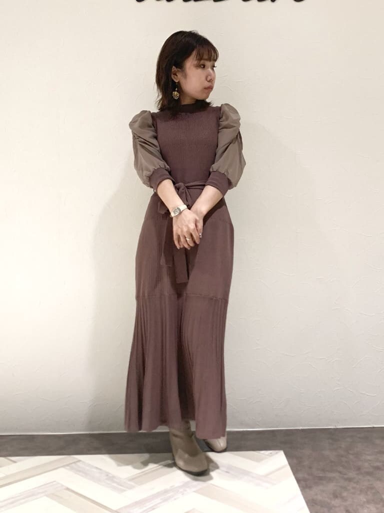 ブラウン系のワンピース、グレー系のトレンチコート、ベージュ系のハンドバッグを着用したレディースの秋コーディネートの5枚目の写真