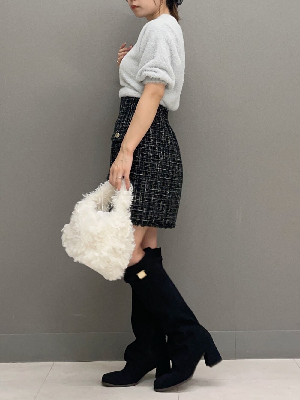 グレー系のニット/セーター、ブラック系のスカート、ホワイト系のハンドバッグを着用したレディースの秋コーディネートの2枚目の写真