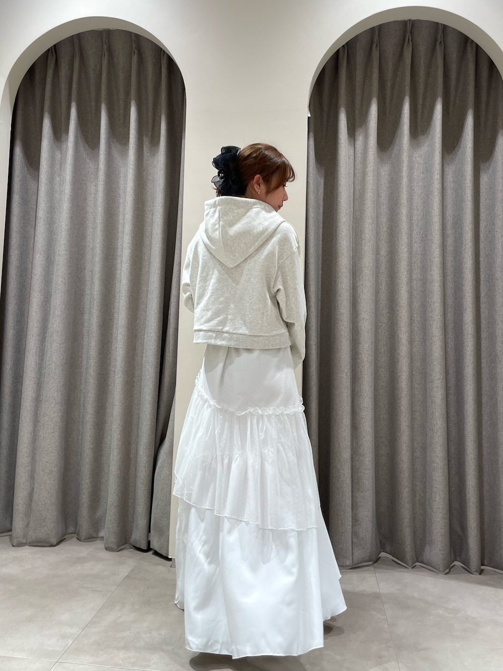 グレー系のパーカー、ホワイト系のスカート、ホワイト系のブーツを着用したレディースの春コーディネートの3枚目の写真