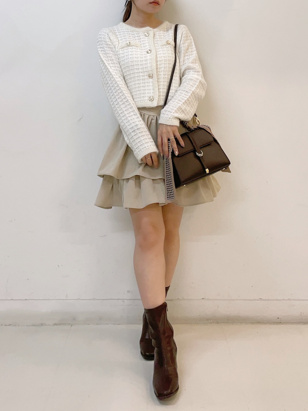 ホワイト系のカーディガン/ボレロ、ホワイト系のスカート、ブラウン系のショルダーバッグを着用したレディースの秋コーディネートの2枚目の写真