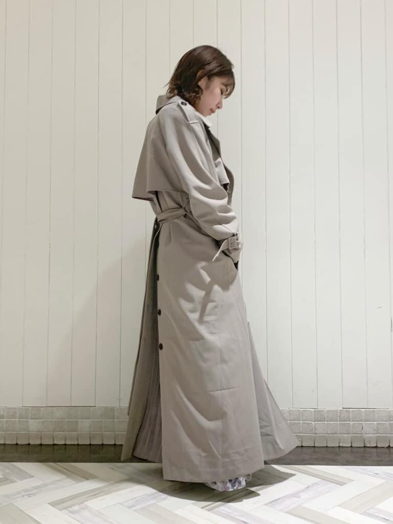 グレー系のトレンチコート、ピンク系のワンピース、ベージュ系のブーツを着用したレディースの秋コーディネートの2枚目の写真