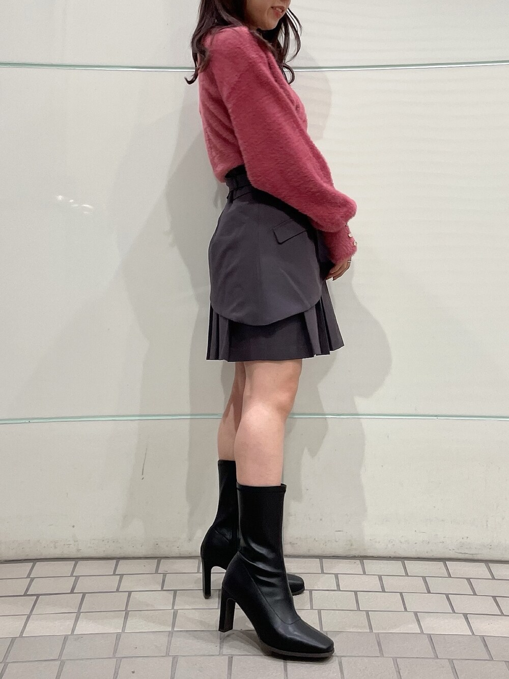 ピンク系のニット/セーター、グレー系のスカート、ブラック系のブーツを着用したレディースの秋コーディネートの2枚目の写真