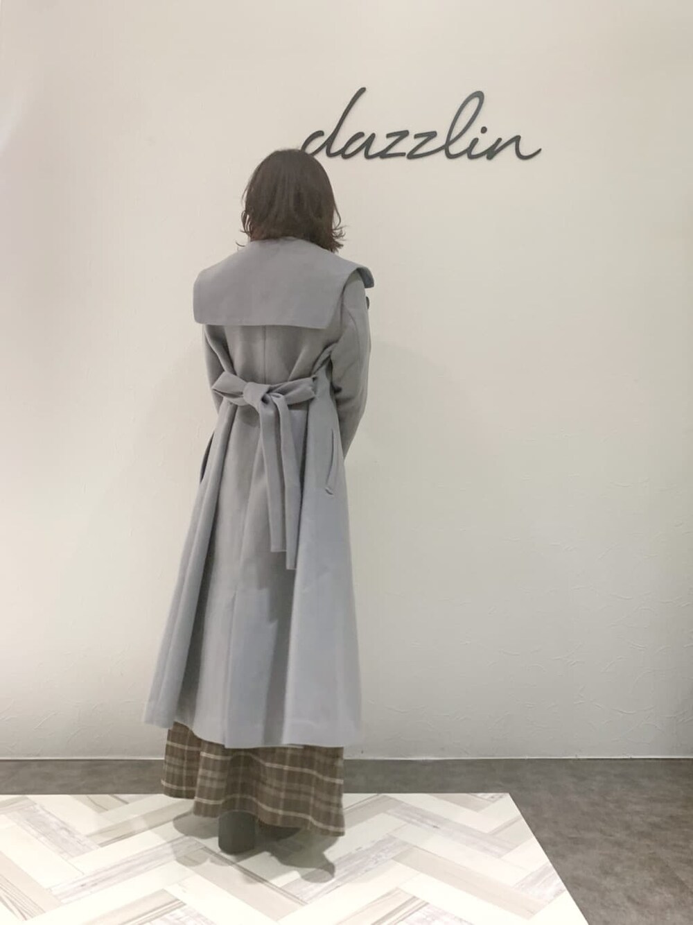 ブルー系のチェスターコート、ブラック系のブーツ、その他のワンピースを着用したレディースの秋コーディネートの6枚目の写真