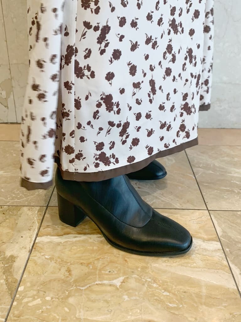 ブラック系のハンドバッグ、ブラック系のブーツ、ベージュ系のワンピースを着用したレディースの夏コーディネートの6枚目の写真