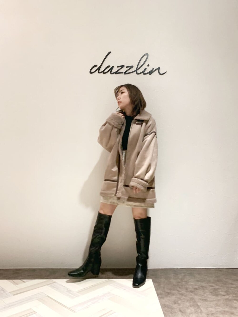 ベージュ系のブルゾン、ベージュ系のスカート、ブラック系のブーツを着用したレディースの秋コーディネートの2枚目の写真