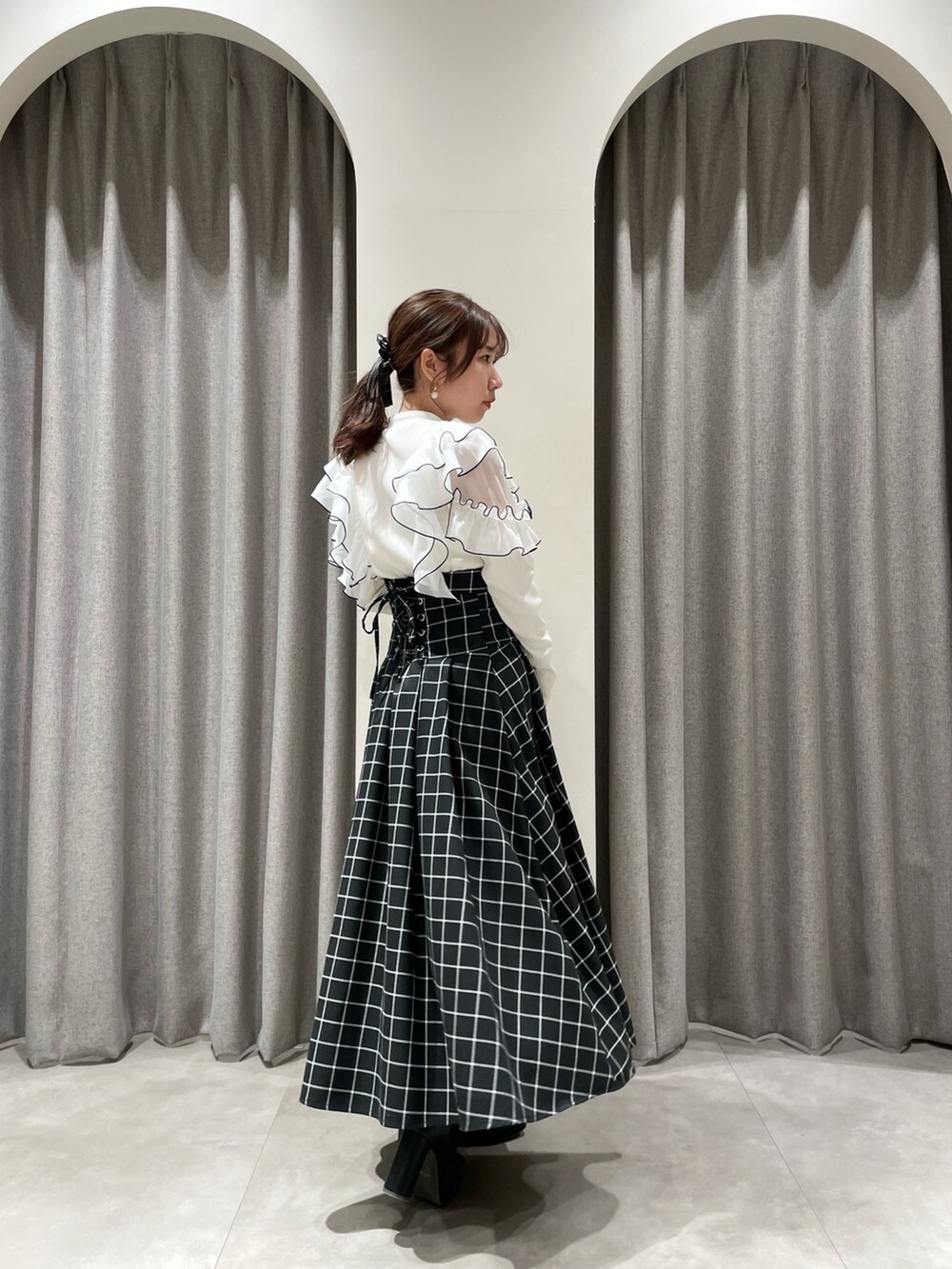 ブラック系のスカート、ホワイト系のTシャツ/カットソー、ブラック系のブーツを着用したレディースの春コーディネートの2枚目の写真