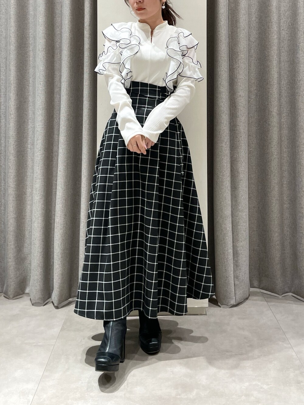 ブラック系のスカート、ホワイト系のTシャツ/カットソー、ブラック系のブーツを着用したレディースの春コーディネートの4枚目の写真