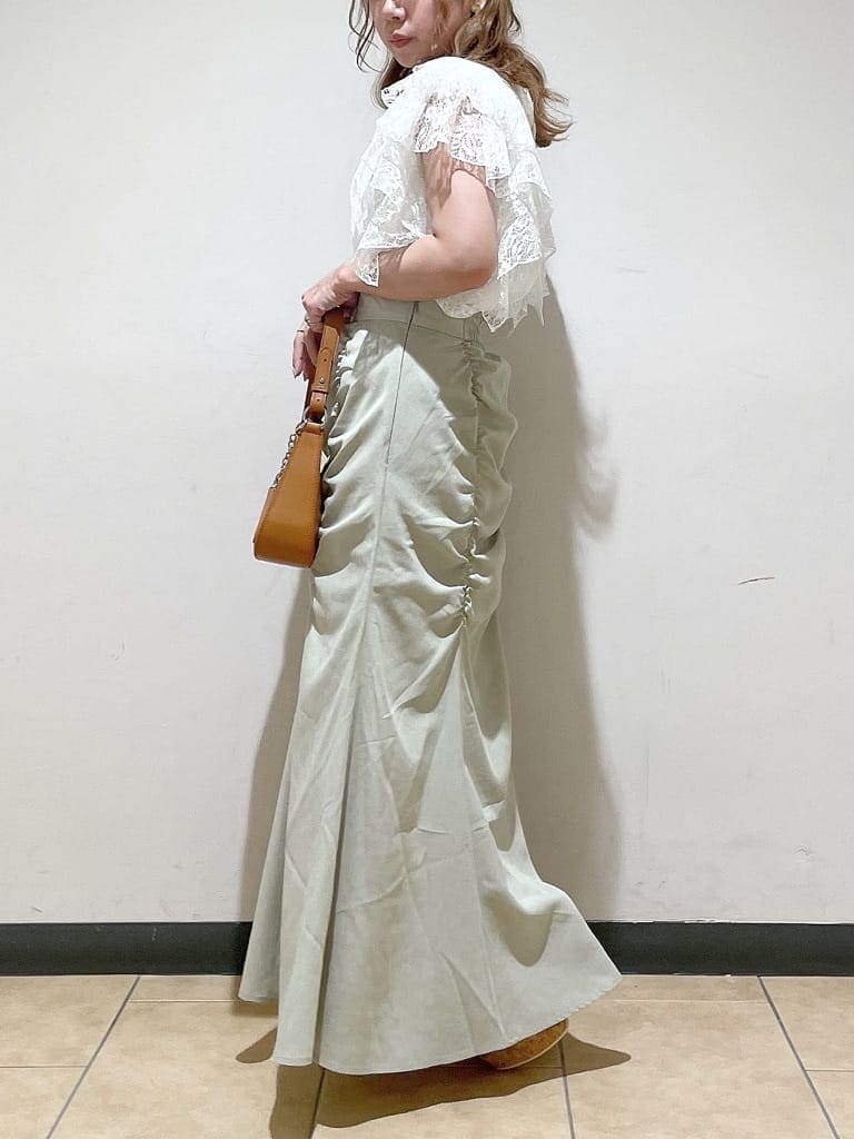 グリーン系のスカート、ブラウン系のハンドバッグ、ホワイト系のシャツ/ブラウスを着用したレディースの夏コーディネートの3枚目の写真