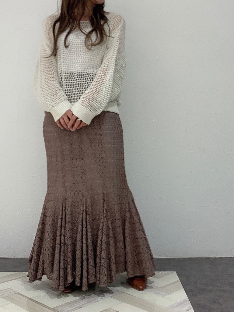 ベージュ系のスカート、ブラウン系のパンプス、ホワイト系のニット/セーターを着用したレディースの春コーディネートの2枚目の写真