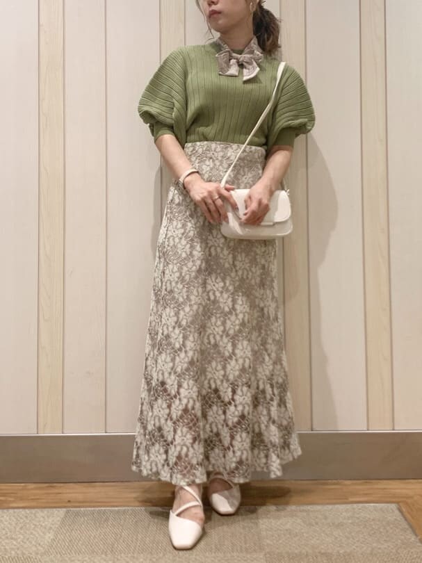 ベージュ系のスカート、ホワイト系のパンプス、グリーン系のニット/セーターを着用したレディースの春コーディネートの4枚目の写真