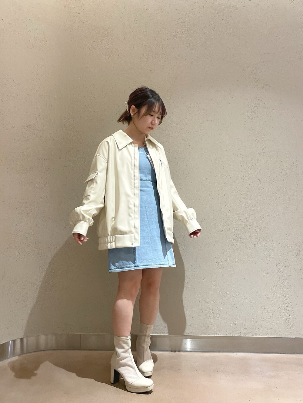 ホワイト系のブルゾン、ブルー系のワンピース、ホワイト系のブーツを着用したレディースの冬コーディネートの3枚目の写真