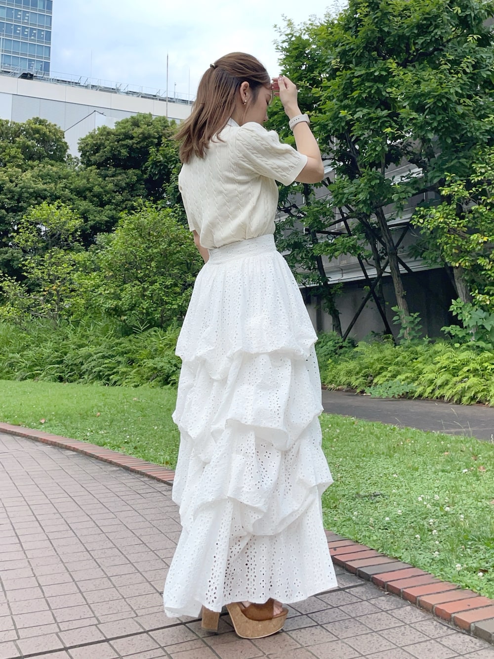 ホワイト系のニット/セーター、ホワイト系のスカート、ブラウン系のボストンバッグを着用したレディースの夏コーディネートの3枚目の写真