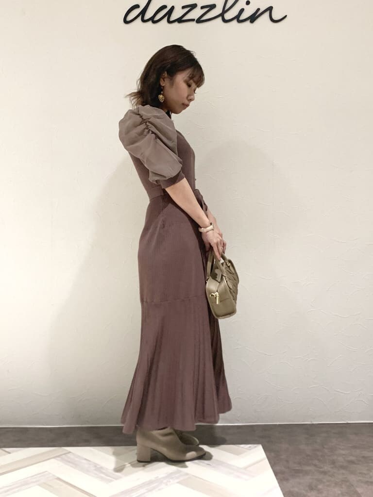 ブラウン系のワンピース、グレー系のトレンチコート、ベージュ系のハンドバッグを着用したレディースの秋コーディネートの2枚目の写真