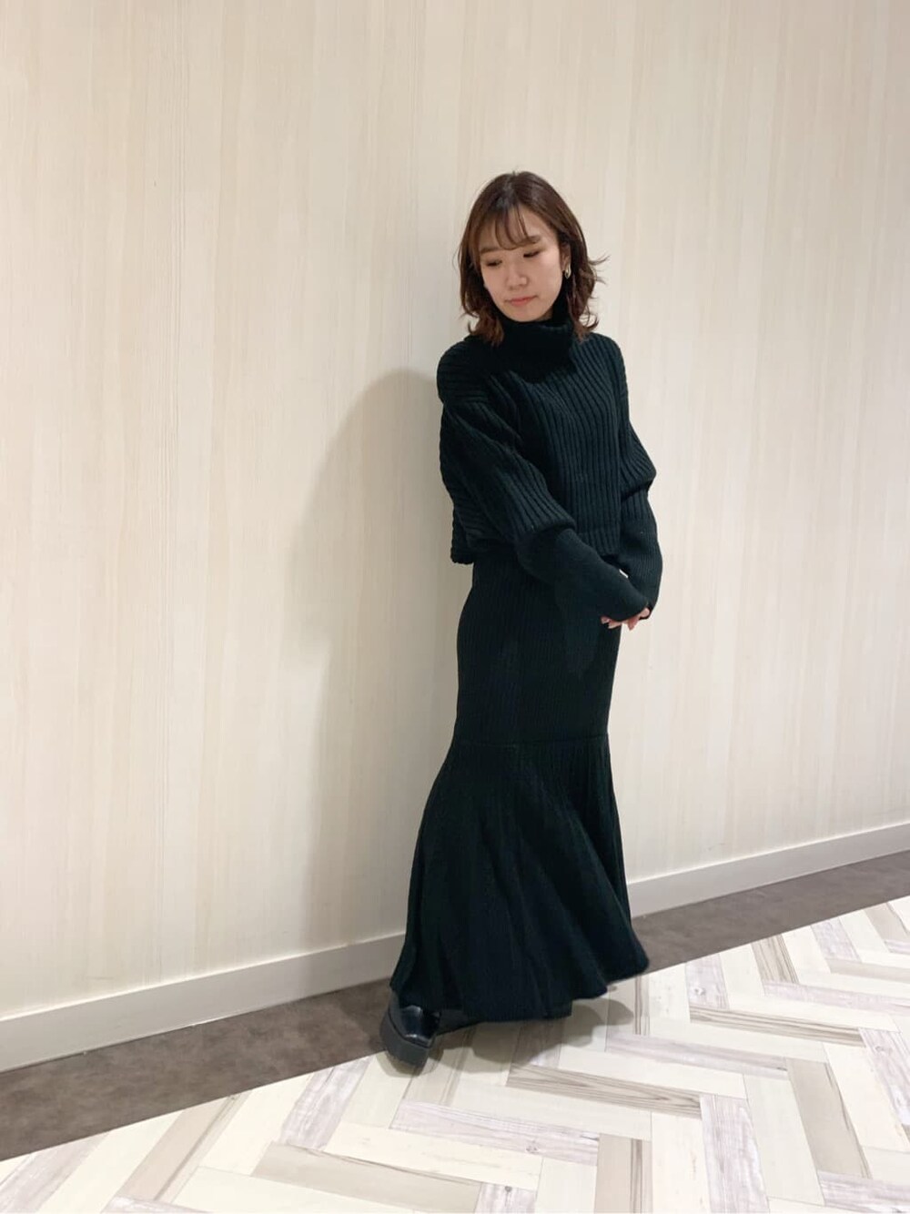 ブラック系のスカート、ブラック系のブーツ、ブラック系のニット/セーターを着用したレディースの秋コーディネートの3枚目の写真